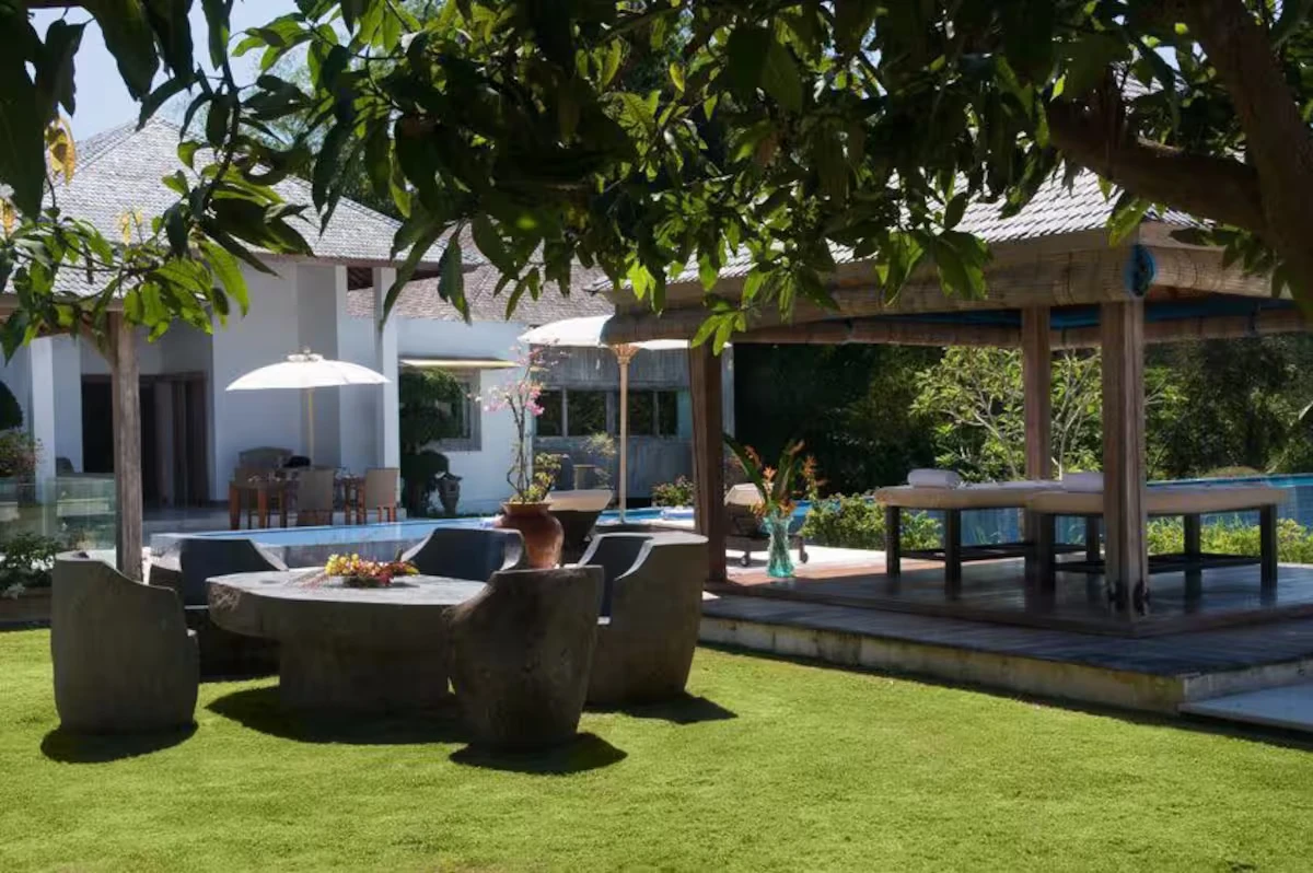 Stone table and chairs on the lawn under a tree
